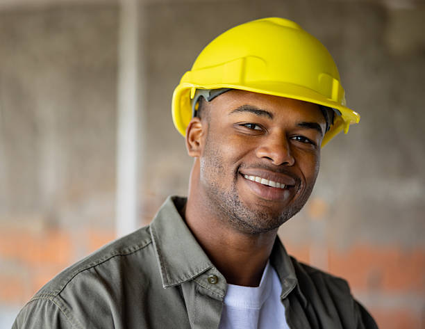 Portrait of a happy African American construction worker smiling at a building site and looking at the camera